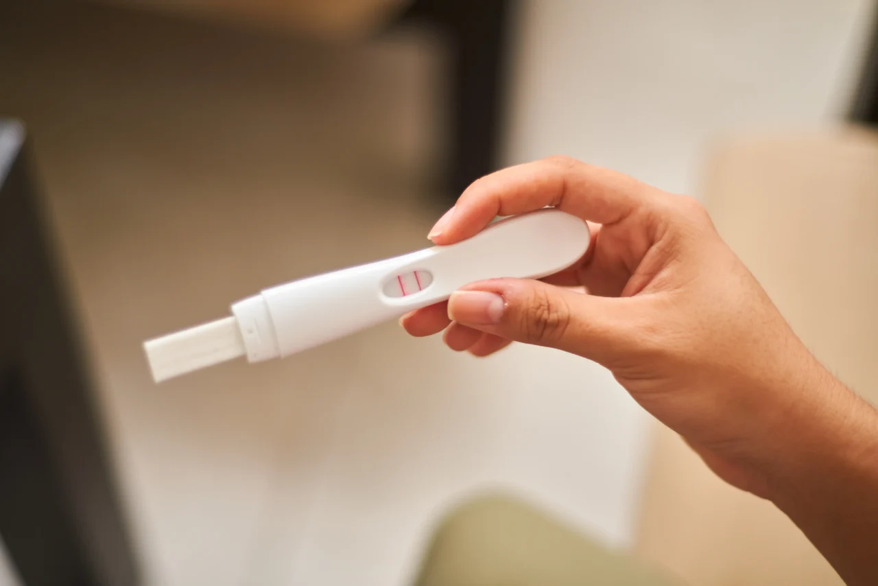 Close up of young latin woman looking at positive pregnancy test